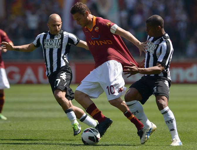 Totti nella morsa dei giocatori del Siena: grande partita per il capitano, trascinatore dei suoi. Afp